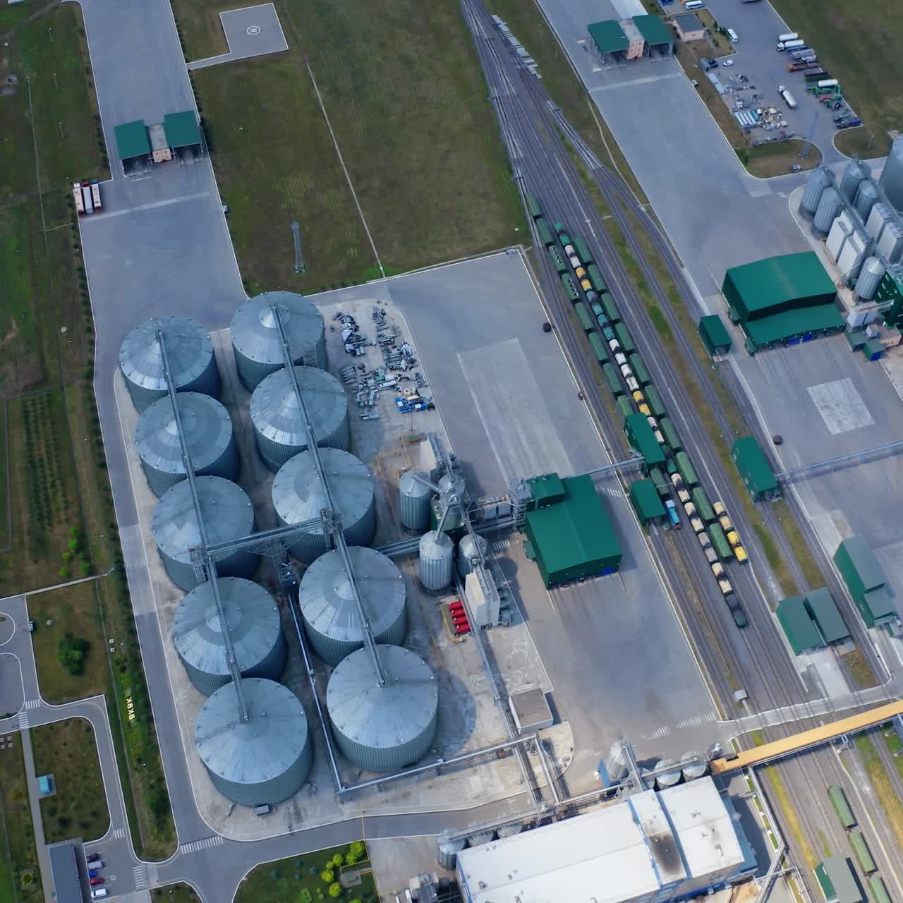 Steel granary storage tanks on field. Flight over modern agriculture complex with silver silos for storing crop. Top view