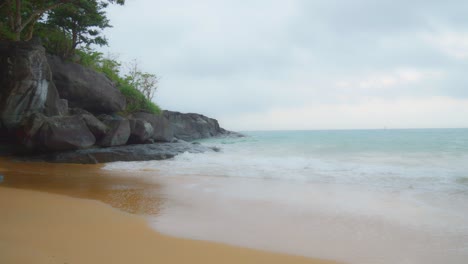 cinematic shot of sea waves breaking on the rocks and sandy beach of con dao island