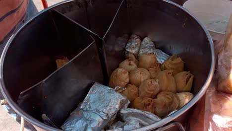 hot tamales being cooked in a big pan during the day, outdoor, medium shot