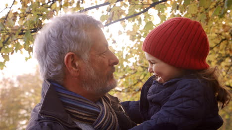 grandfather walking with granddaughter in autumn countryside