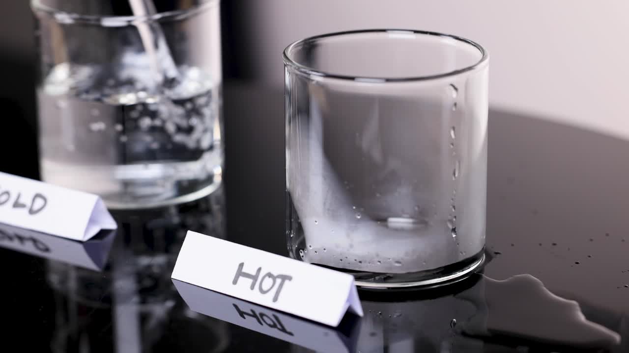 Hot and cold water poured into labeled glasses, showing condensation, steam, static camera, studio lighting