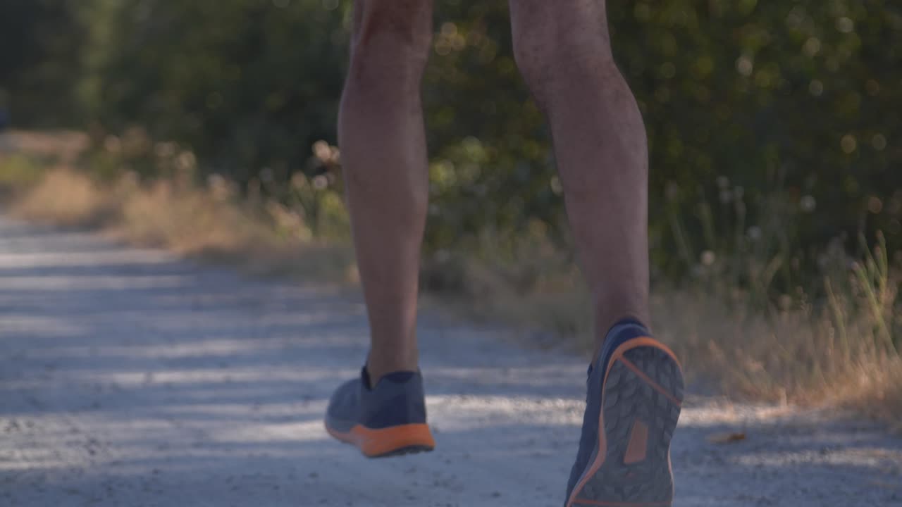 Professional runner running fast on dirt path in smooth slow motion tracking shot