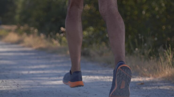 Corridore professionista che corre velocemente su sentiero sterrato con ripresa in slow motion