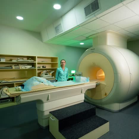 male patient coming into the room with modern mri machine. female medical worker near the modern magnetic resonance imaging scan in clinic.