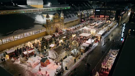 aerial overlooking illuminated lansdowne christmas market at night beside aberdeen pavilion in ottawa. slow pan right