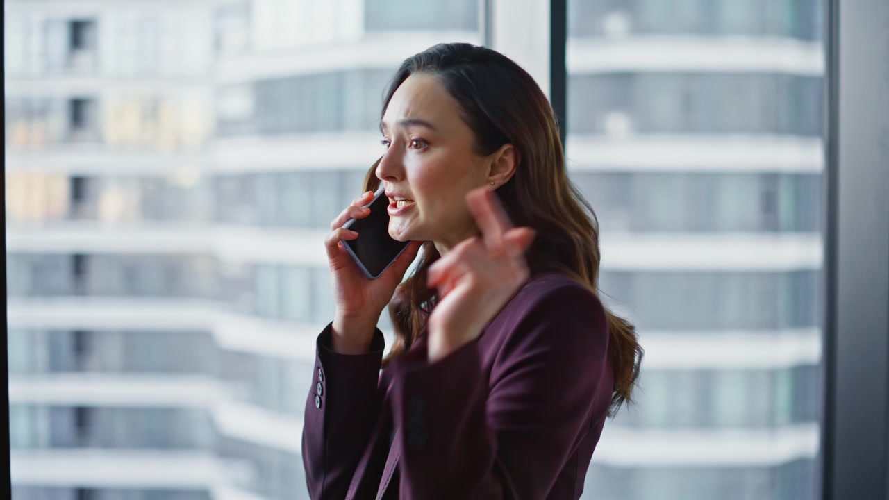 Emotional manager talking smartphone at work standing panoramic office closeup
