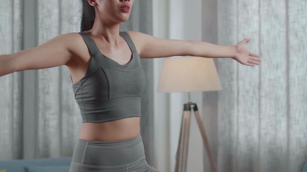retrato en primer plano de una joven asiática atlética en ropa deportiva haciendo yoga en la postura del árbol en la alfombra en casa