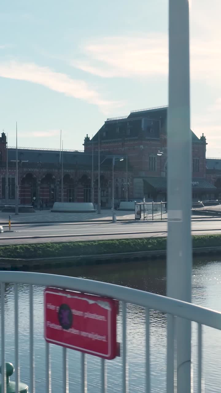 Stazione ferroviaria di Groningen con canale e traffico in una giornata di sole.
