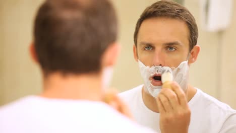 man shaving himself in front of a mirror