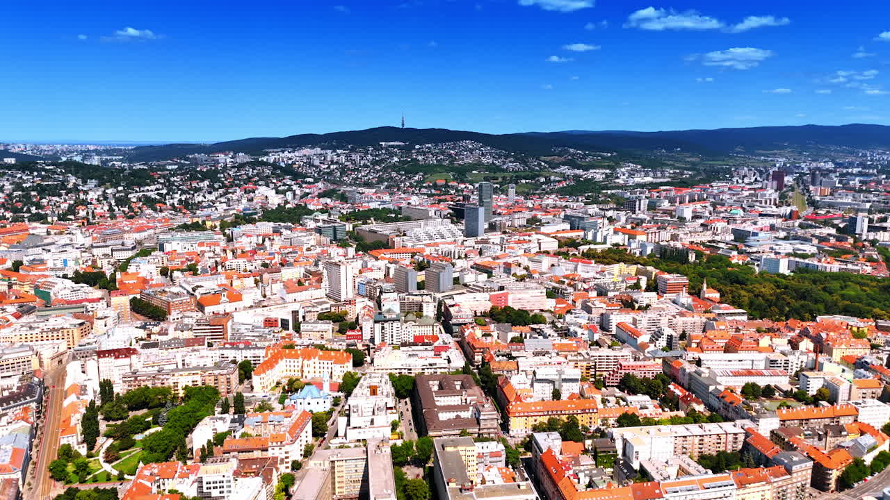 Sun-dazzled panorama of modern Bratislava, Slovakia. Green mountain range at backdrop. Aerial view.