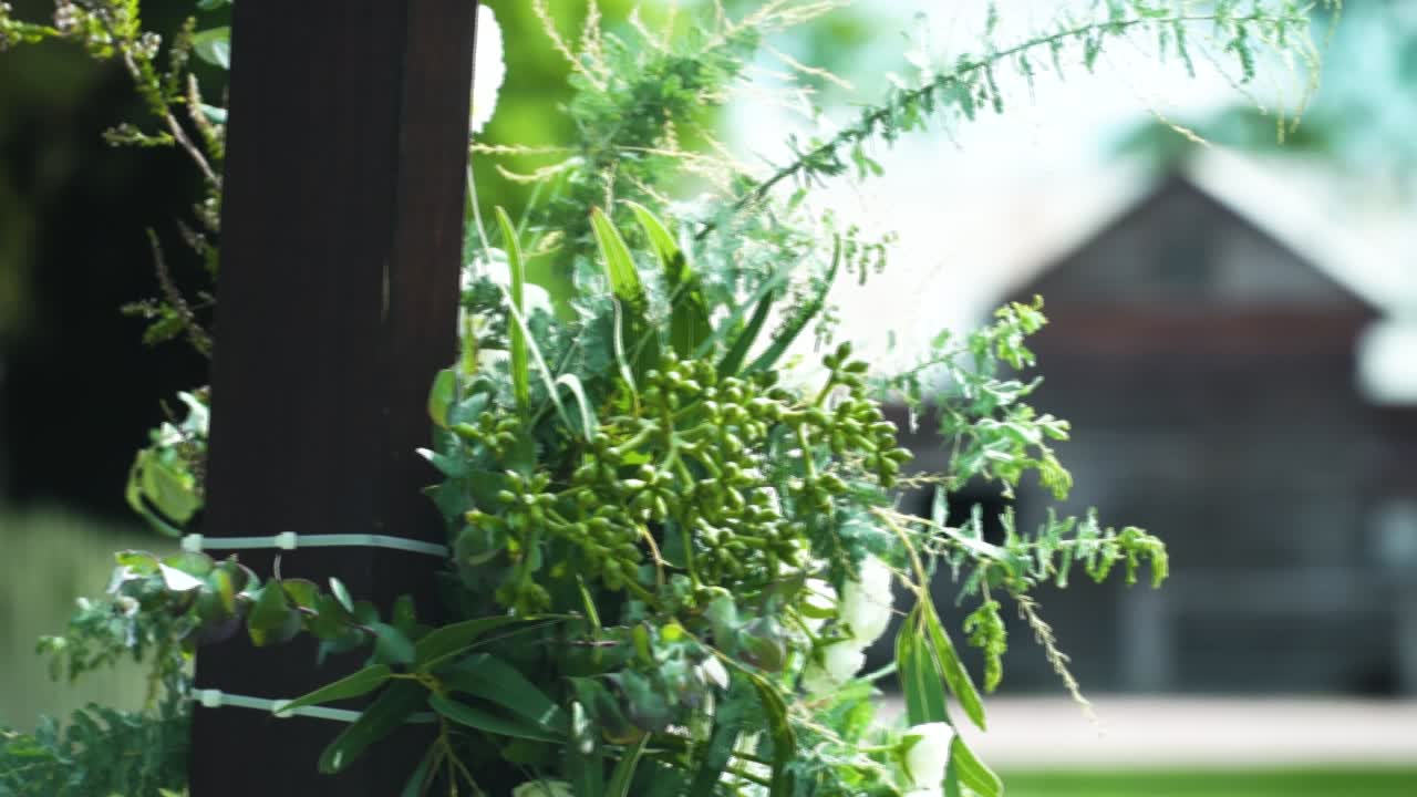 배경에 보케 구조가 있는 목조 웨딩 아치의 꽃 장식 - 야외 결혼식 - 클로즈업 샷