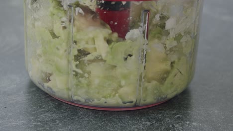 close up of an manual kitchen machine cutting and mixing up an avocado and onions