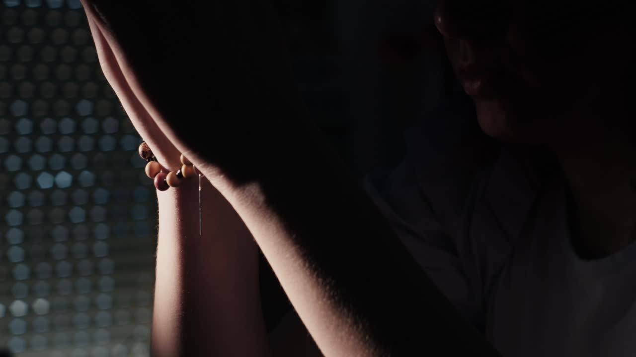 Dramatic Close-up of Person's Arms and Bracelet in Low Light