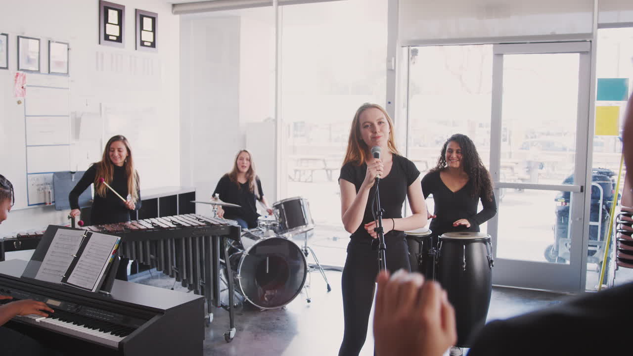 un maestro observando a los estudiantes de la escuela de artes escénicas tocando en la banda en el ensayo