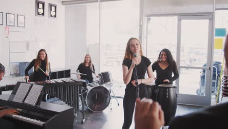 un maestro observando a los estudiantes de la escuela de artes escénicas tocando en la banda en el ensayo
