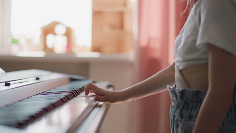 el niño aprende a tocar el piano de pie contra la ventana