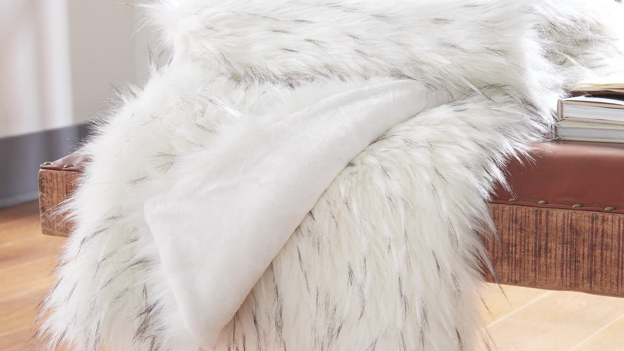 Wide slow pan shows fur blanket across leather bench in soft light