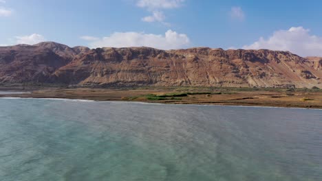 Deadsea-fly-over,-desert-flourishing-after-the-rains,-fly-over,-red-mountain-background