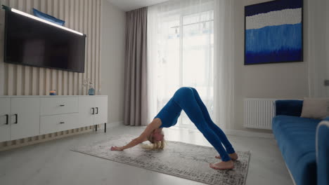 una hermosa mujer joven realiza ejercicios sin salir de casa. entrenamiento de equilibrio y estiramiento en aislamiento. ejercicios remotos en casa