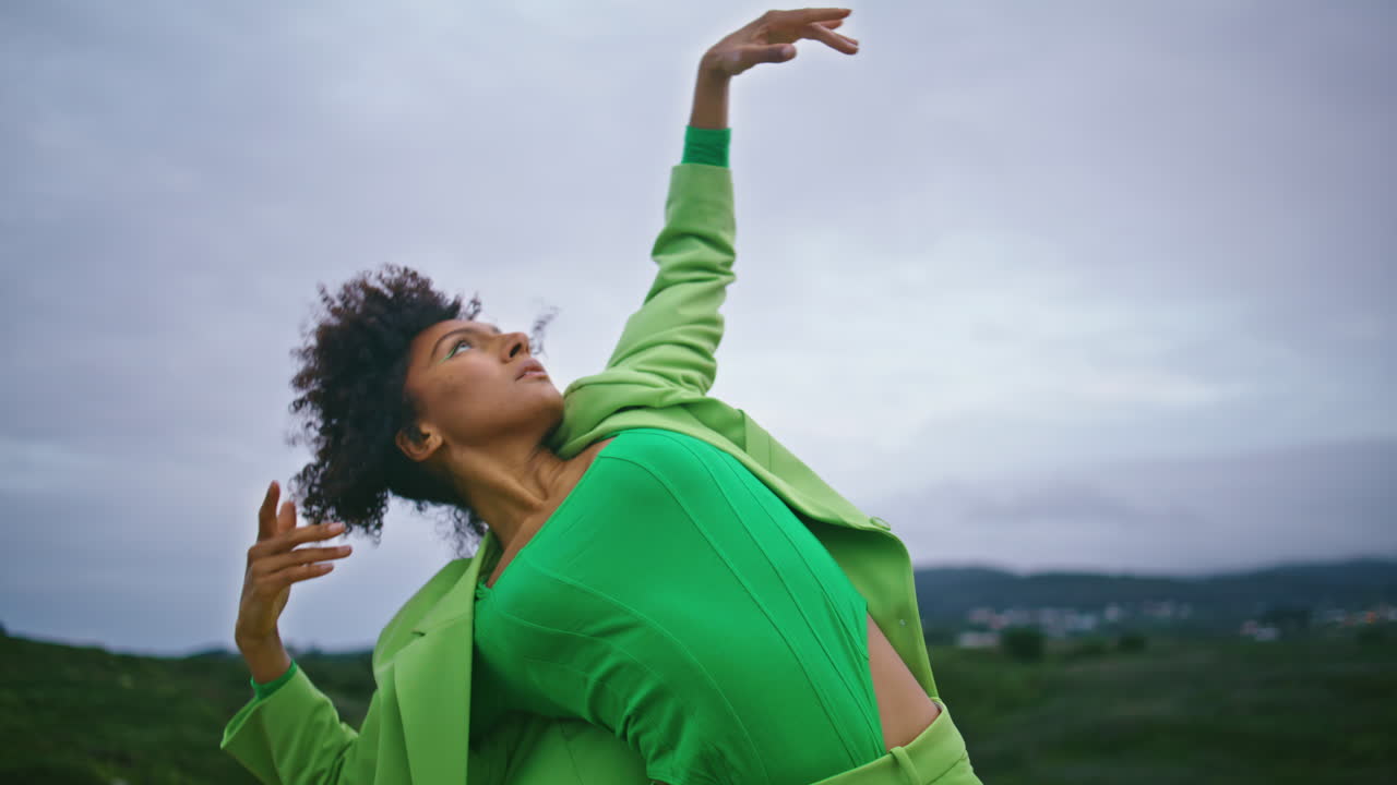 artista mujer bailando coreografía moderna expresiva en frente cielo gris de cerca.