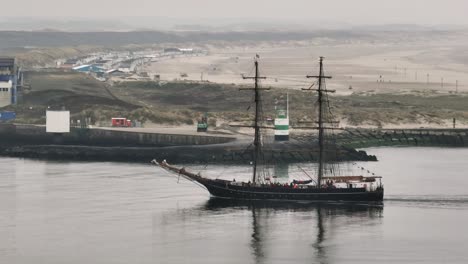 traditional dutch sailing boat enters port of ijmuiden, aerial arc shot