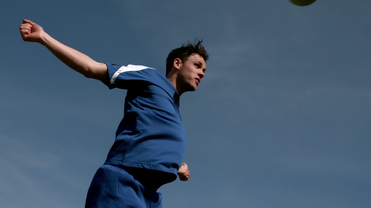 jugador de fútbol encabezando la pelota bajo el cielo azul