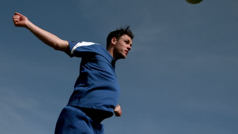 jugador de fútbol encabezando la pelota bajo el cielo azul