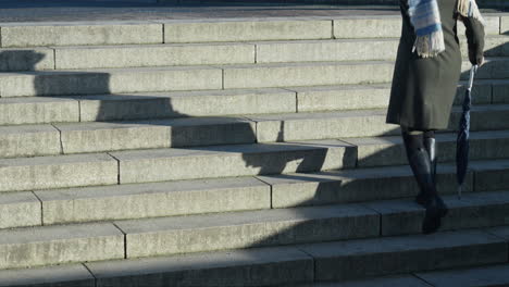 woman walking up stone steps casting a long shadow