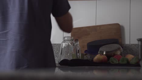 man wipes washed dishware and places them in kitchen cabinet - static, medium shot