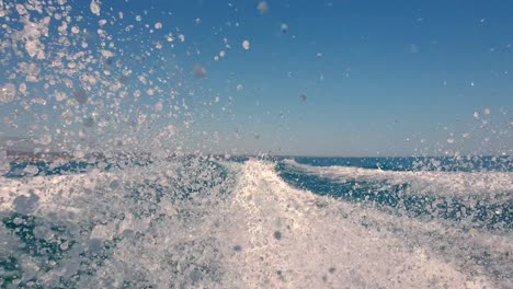 low angle perspective of motor boat wake trail and water spray on sea surface