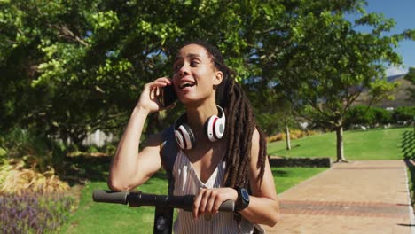 African-american-woman-on-scooter-talking-on-smartphone