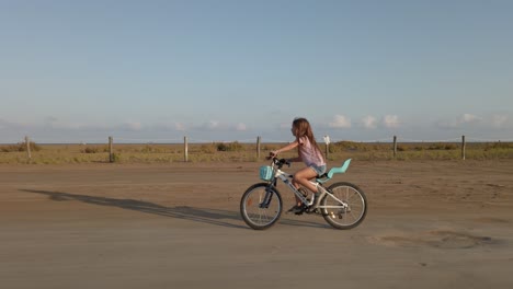 long red hair girl riding a bike in street a sunny desert countryside