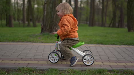 Lächelndes-Kleinkind-Beim-Ersten-Versuch-Mit-Dem-Fahrrad.-Fröhlicher-Junge,-Der-Draußen-Fahrrad-Fährt.