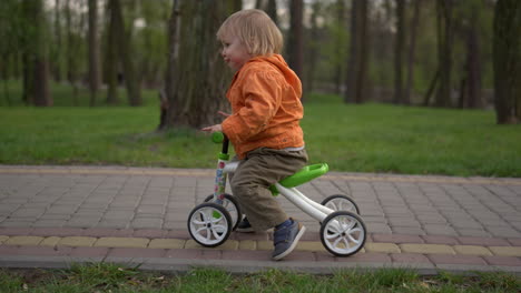 smiling toddler making first try on bike. happy boy riding on bicycle outdoors.