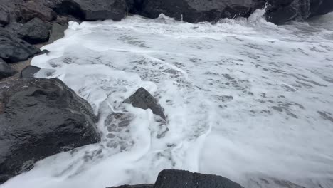 closeup of waves rolling up on sand and stone in oregon, usa