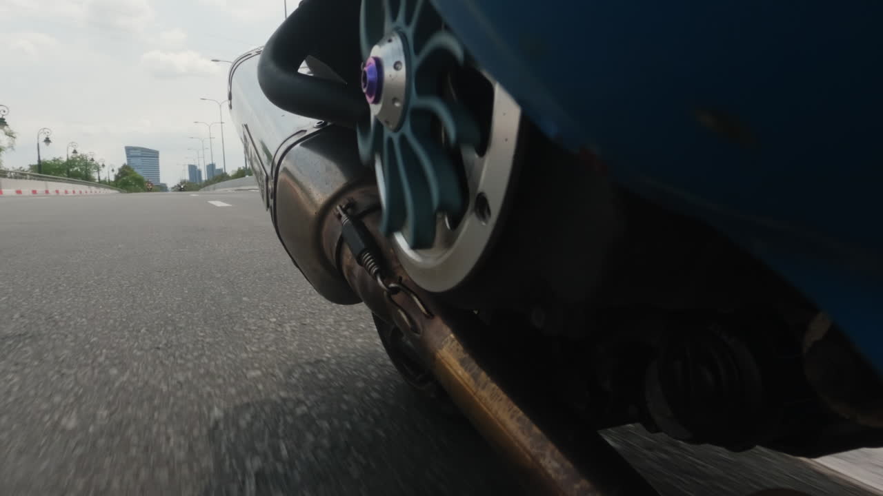 Low-angle view of a motorcycle's exhaust while riding on a road