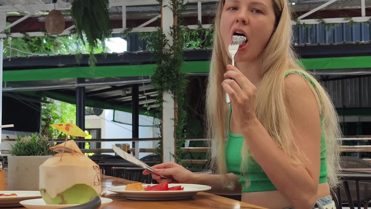 열대 야외 카페에서 점심을 먹는 여자