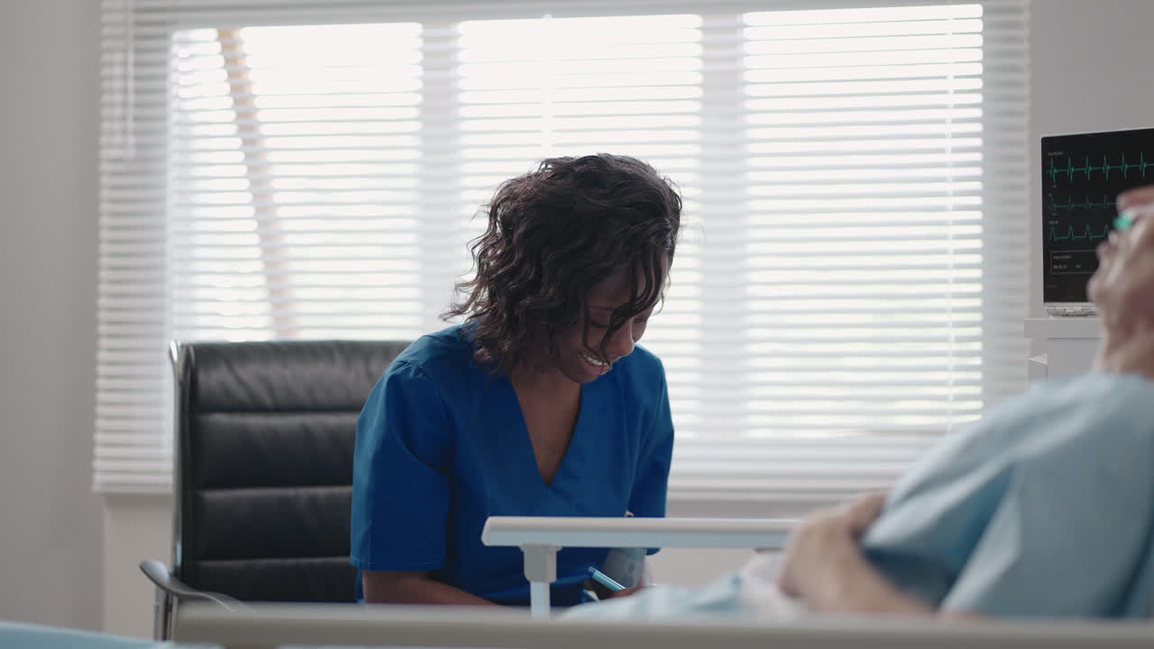 A black woman cardiologist doctor is talking to an old man patient lying on a hospital bed discussing rehabilitation after recovery. an infectious disease neurologist discusses a treatment strategy