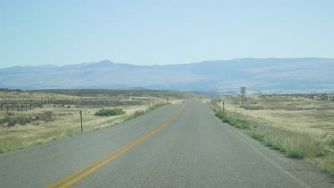 open desert road through car window while driving