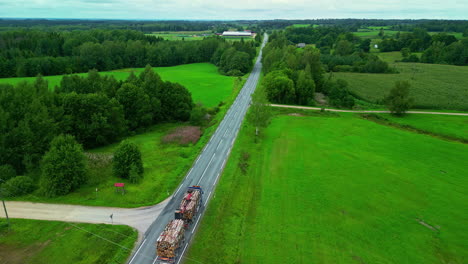 Eine-Aufnahme-Aus-Der-Vogelperspektive-Eines-Lastwagens,-Der-Holz-Transportiert-Und-Durch-Eine-Grüne-Landschaft-Fährt