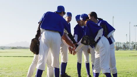 Grupo-Diverso-De-Jugadoras-Y-Entrenadoras-De-Béisbol,-Apiñadas-Y-Haciendo-Pila-De-Mano-En-El-Campo