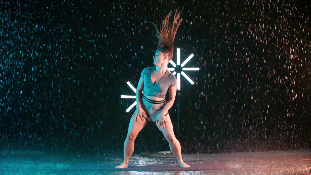 Woman dancer spinning wet hair in the rain in super slow motion