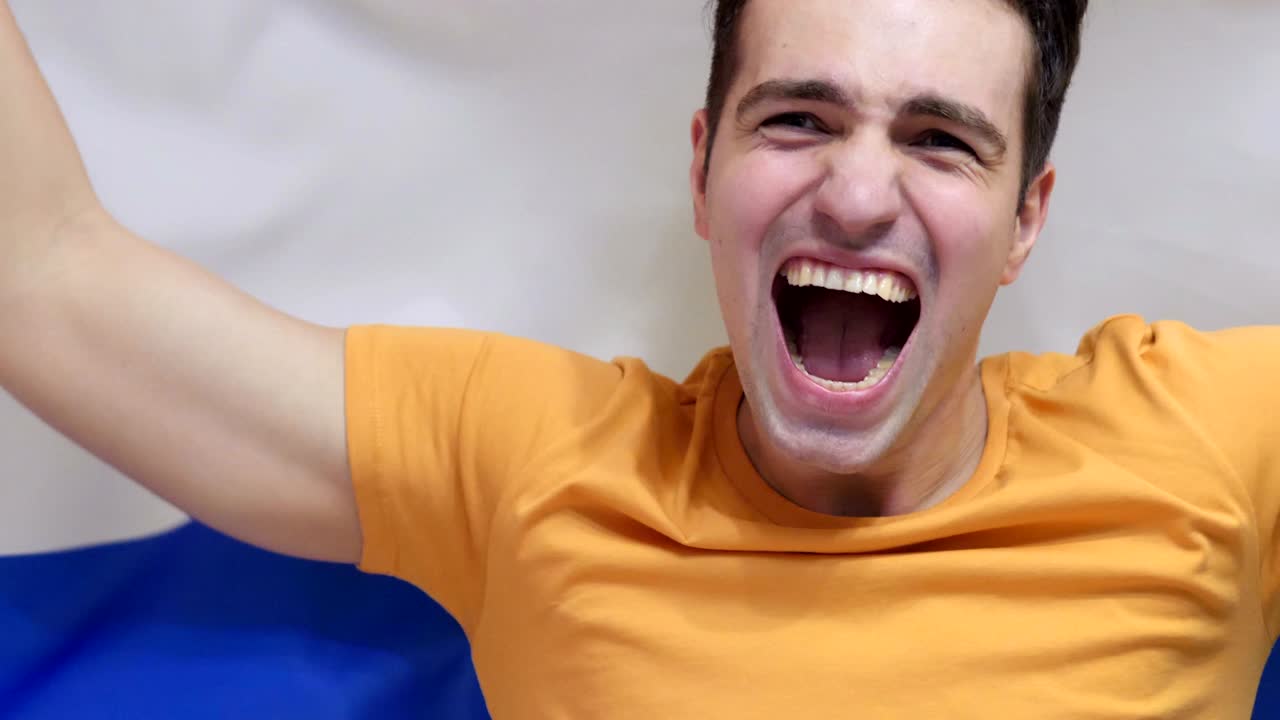 un joven celebra sosteniendo la bandera de los países bajos en cámara lenta.