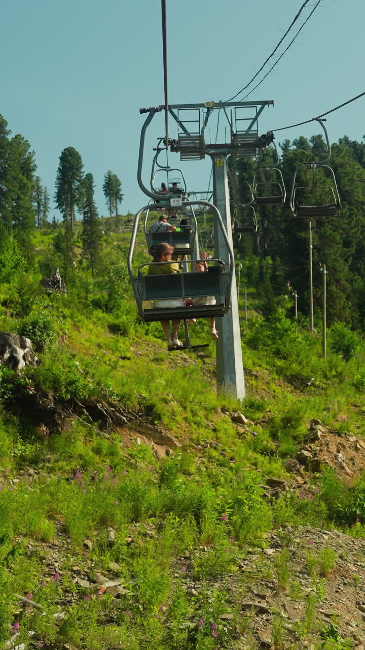 Tourists lift to top of mountain on cable car in summer. Enjoying leisure time together on holiday. Hotel area surrounded by hills and forest slow motion