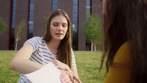 Two-female-caucasian-students-studying-outside-the-university-campus