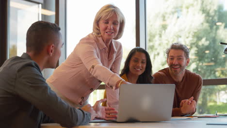 multi-cultural business team meeting around laptop in modern office