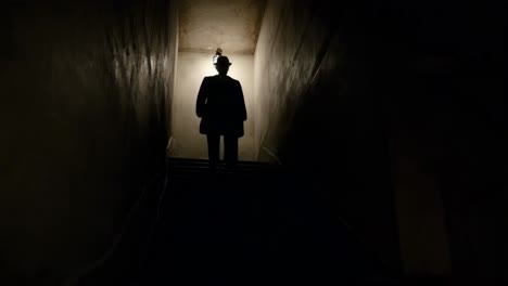 man walking upstairs in a dark basement