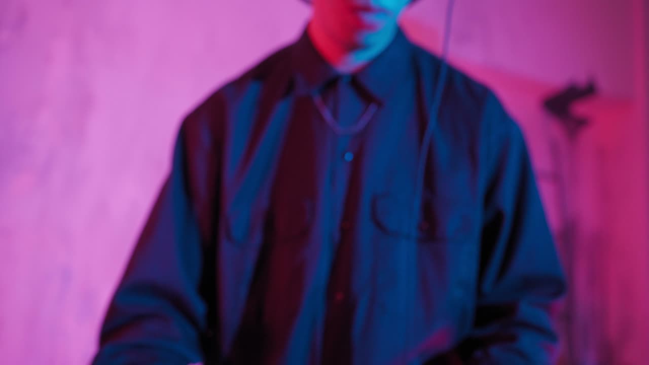 un dj moderno de apariencia asiática realiza una pista de música con iluminación de neón.