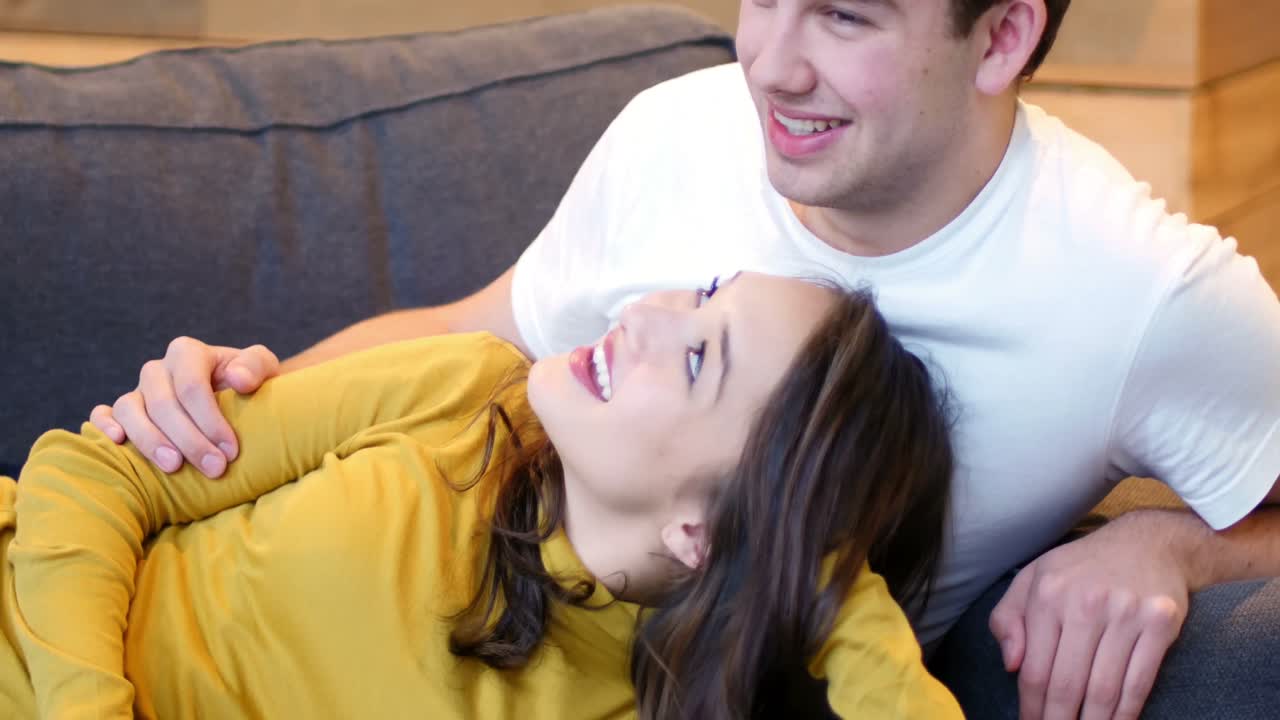 웃는 커플이 거실의 소파에서 상호 작용하고 있습니다.