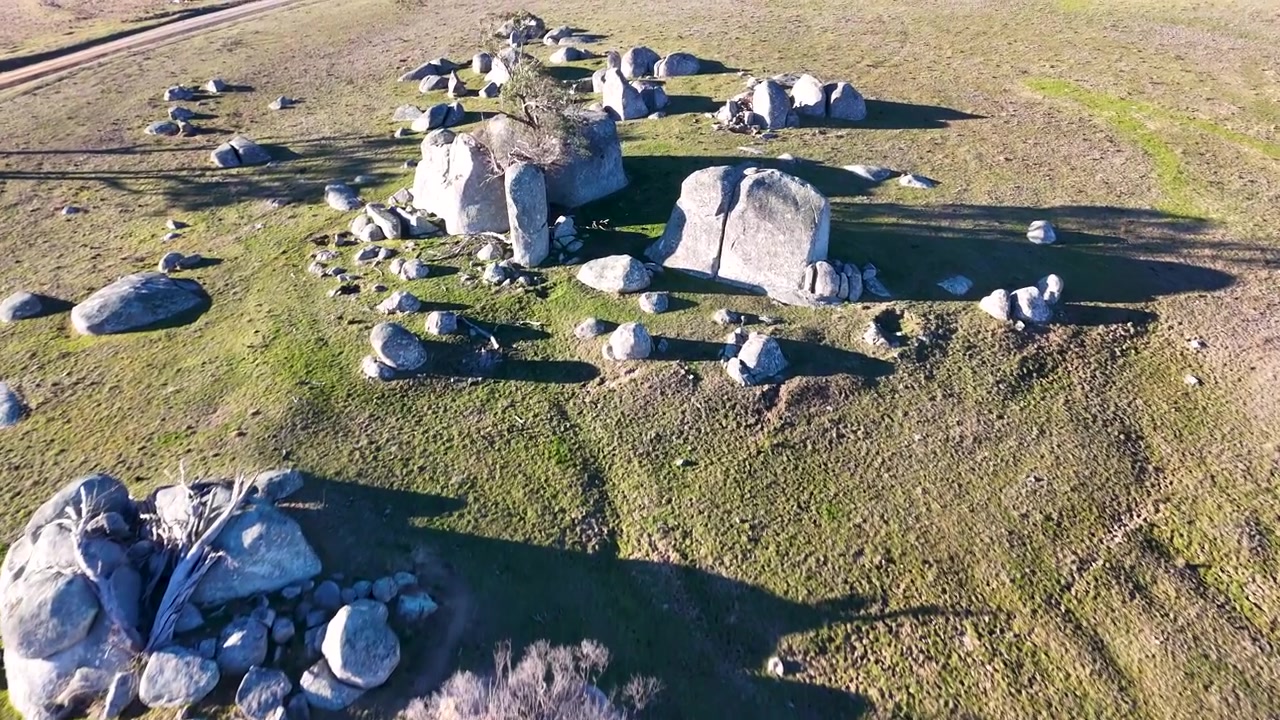 Ujęcie z drona opadającego nad dużymi granitowymi głazami na trawiastych polach w pobliżu Uralla w Australii